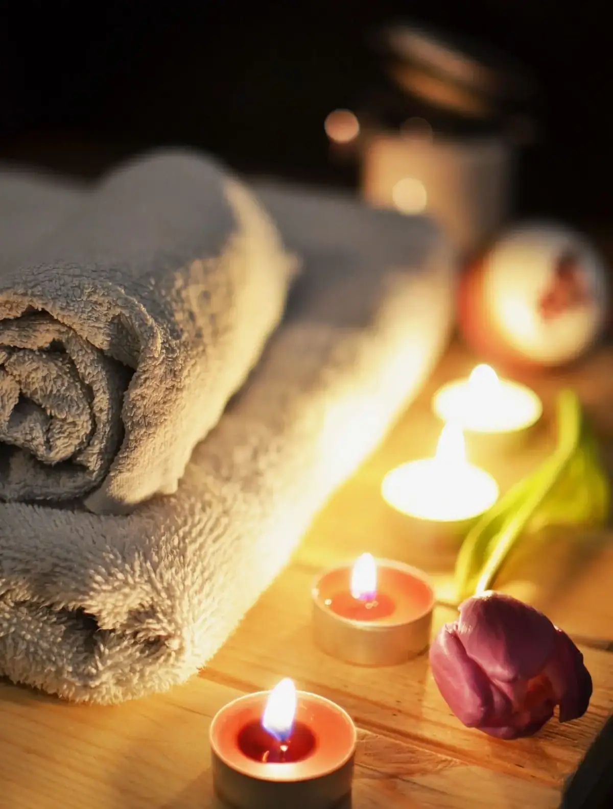 Folded towels, a rose, and four lit candles